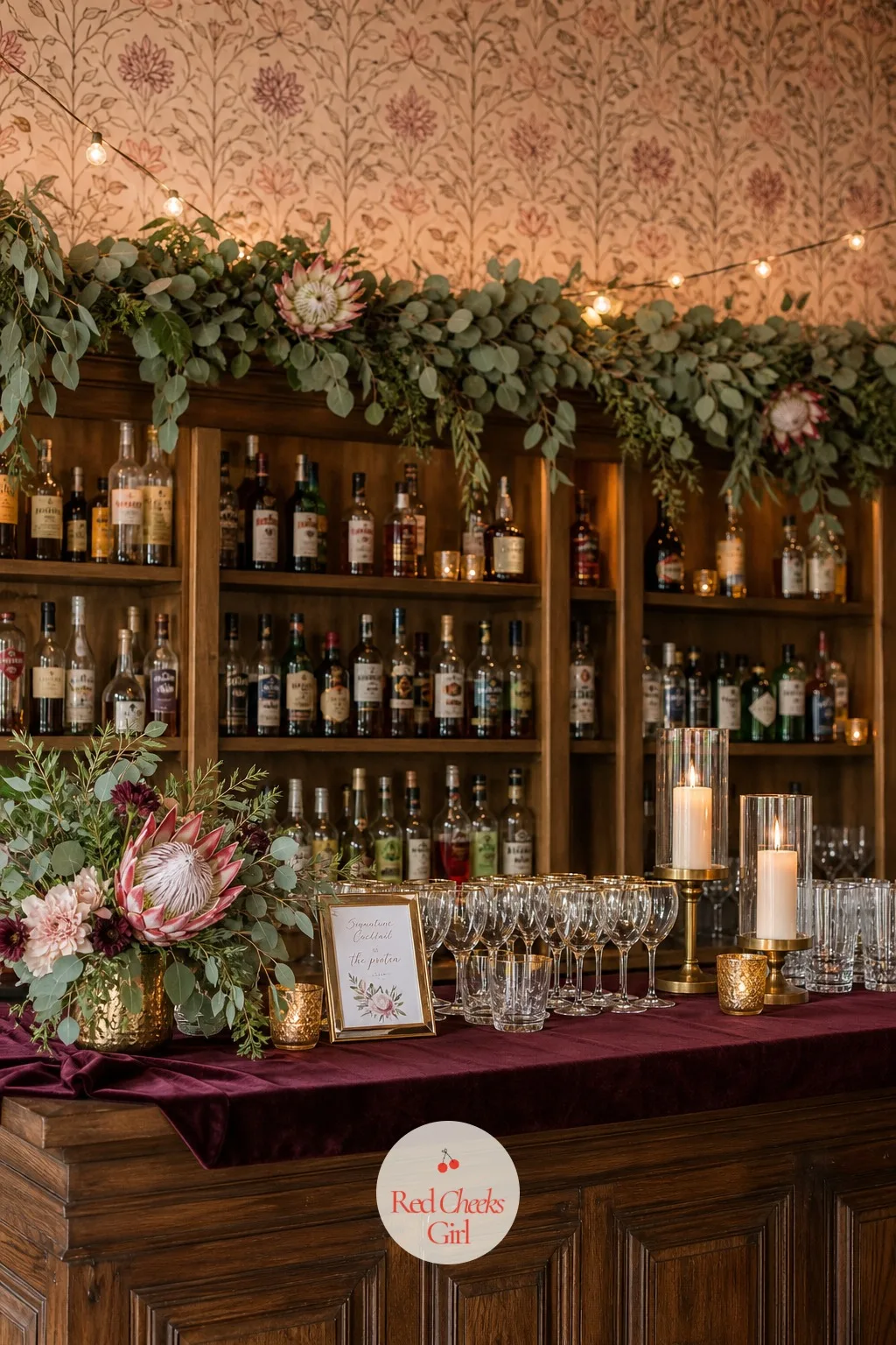 The Bar Backdrop Strung With Protea And Eucalyptus Garland — Behind the bartender, a garland of eucalyptus runs the length of the shelf or back wall, with a