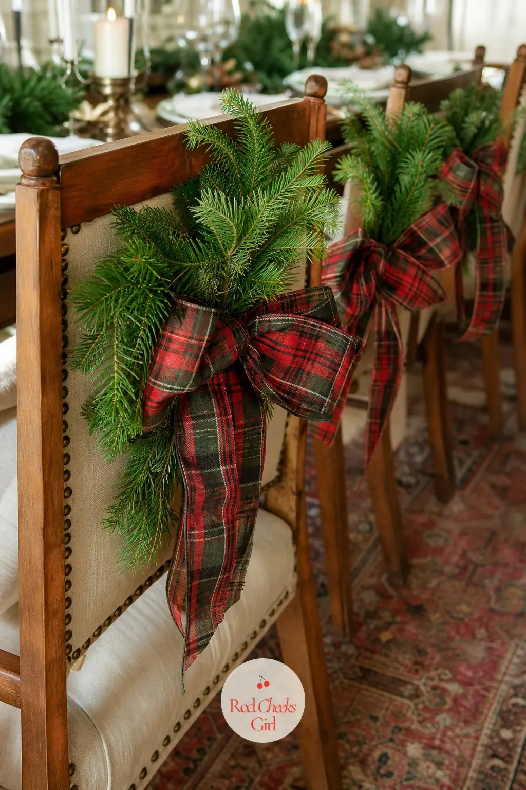 Chair Backs Dressed In Tartan And Greenery — Each dining chair wears a small pine sprig clipped to the top rail and tied off with a short length of tartan