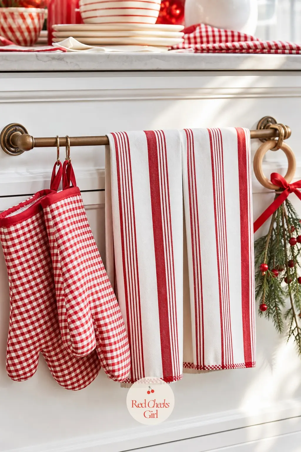 The Kitchen Towel Bar — Four candy stripe towels loop over the bar in rotation, with a pair of gingham oven mitts hanging just beside them. Red and white