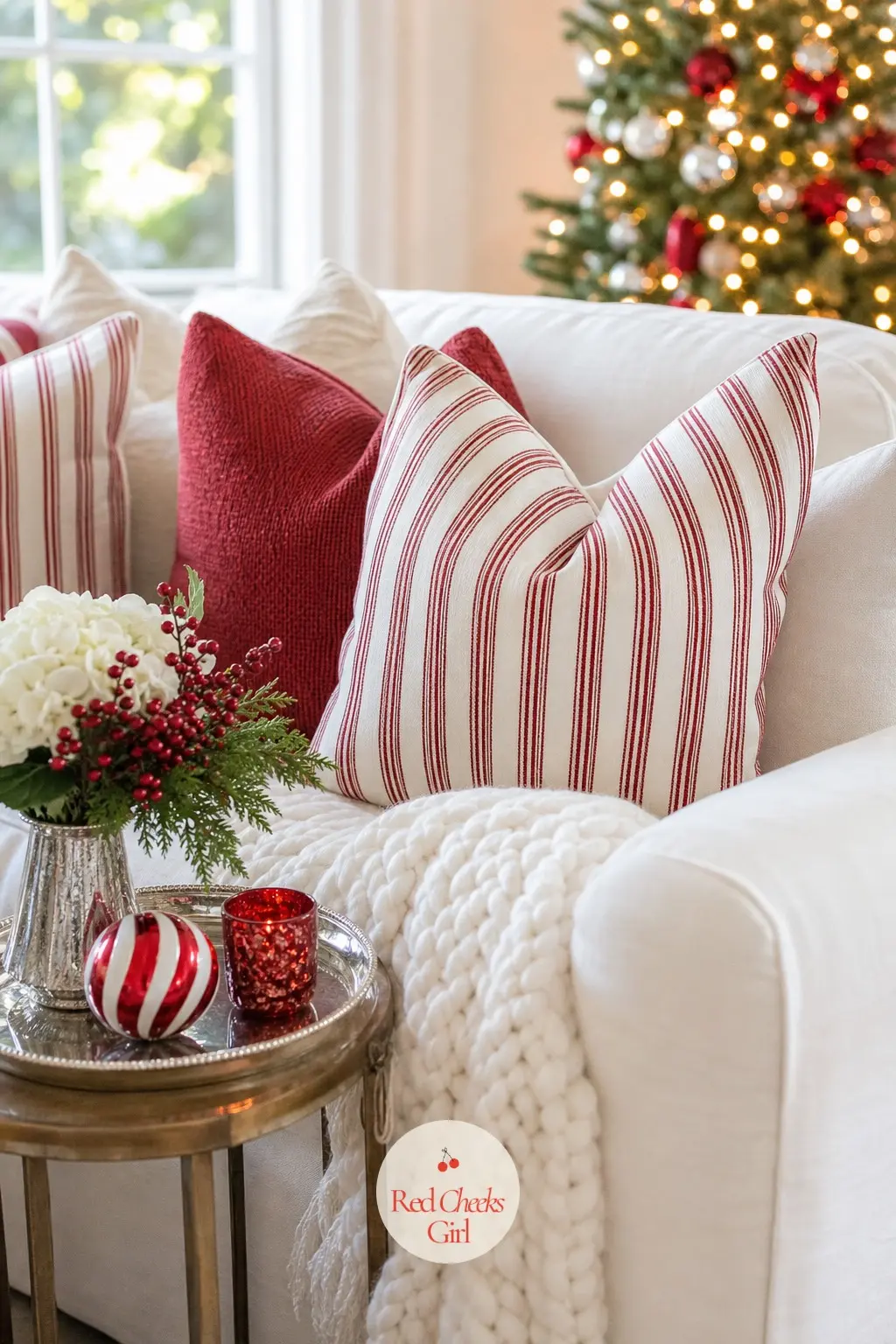 The Living Room Sofa — Four candy stripe cushions anchor the sofa, with one chunky white knit throw folded loosely over the arm so the stripe reads from across