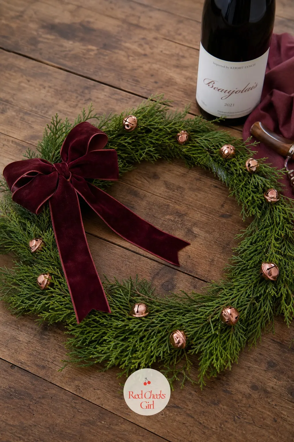 The Burgundy Velvet Bow and Copper Bell Wreath for the Wine Tasting Table — Laid flat in the centre of a wine tasting table, this wreath carries a deep