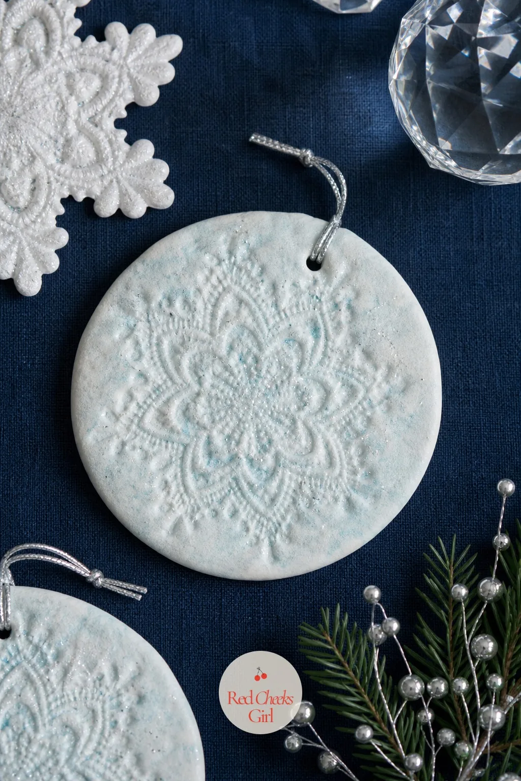 Doily-Pressed Snowflake Discs — A paper doily pressed firmly into soft dough and peeled away leaves a lace pattern no cutter could manage, and you probably