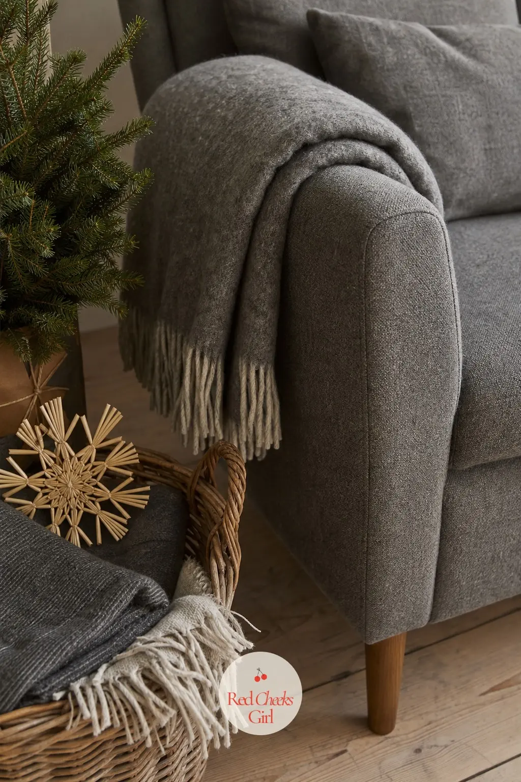 The Armchair Corner, Thrown in Wool and Grey — One armchair, one basket of folded blankets, one small woven straw star tucked into the top fold. Scandinavian