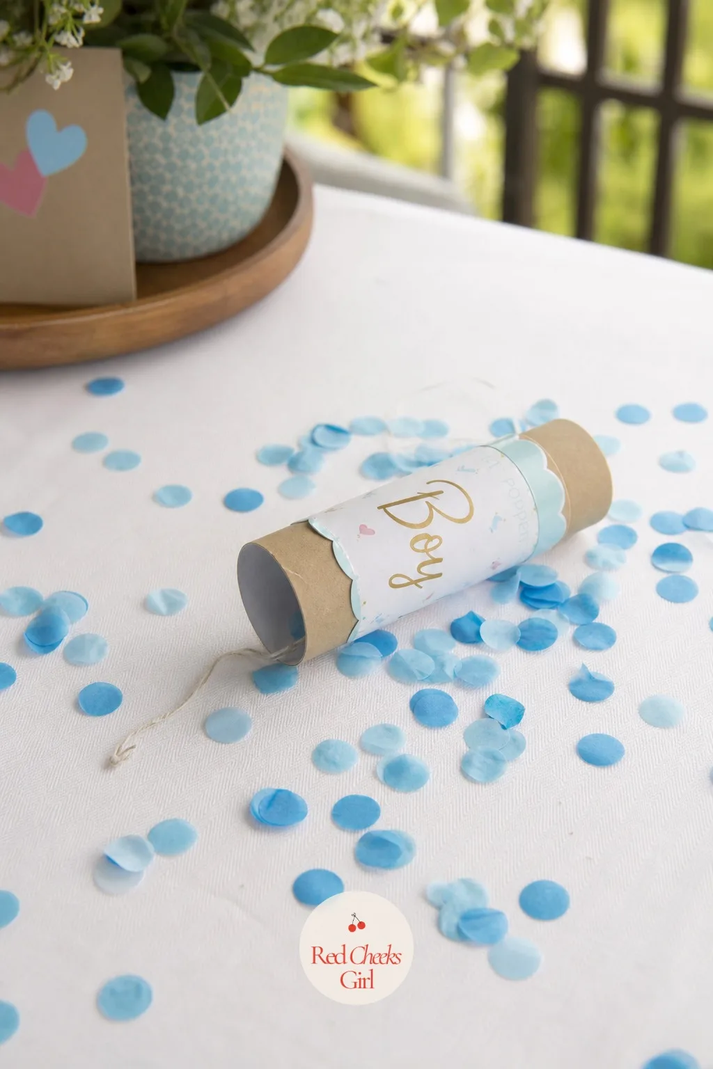 The Confetti Popper — No swing, no smash, just a small tube she points up and a tab she pulls, and the colour is out before anyone has time to brace for it.