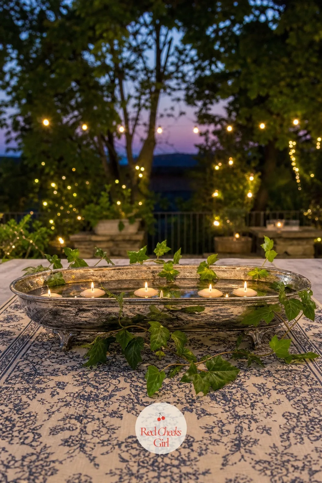 Floating Candles in a Low Silver Trough — An evening garden reception needs light low on the table, not glare, and a trough of floating candles gives exactly