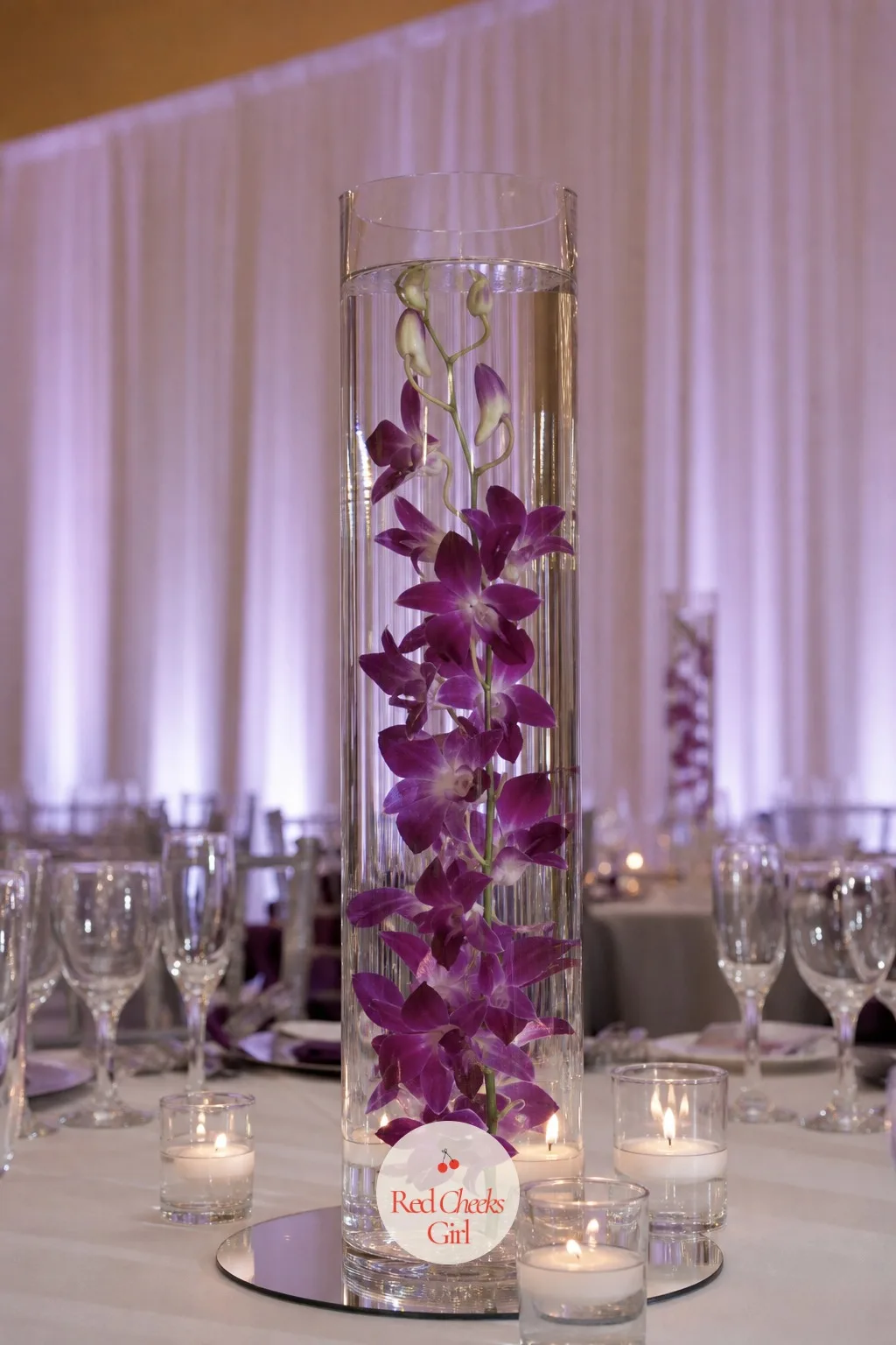 Submerged Orchids in a Tall Glass Cylinder — A modern reception wants something with a little visual trick to it, and a submerged orchid stem delivers that