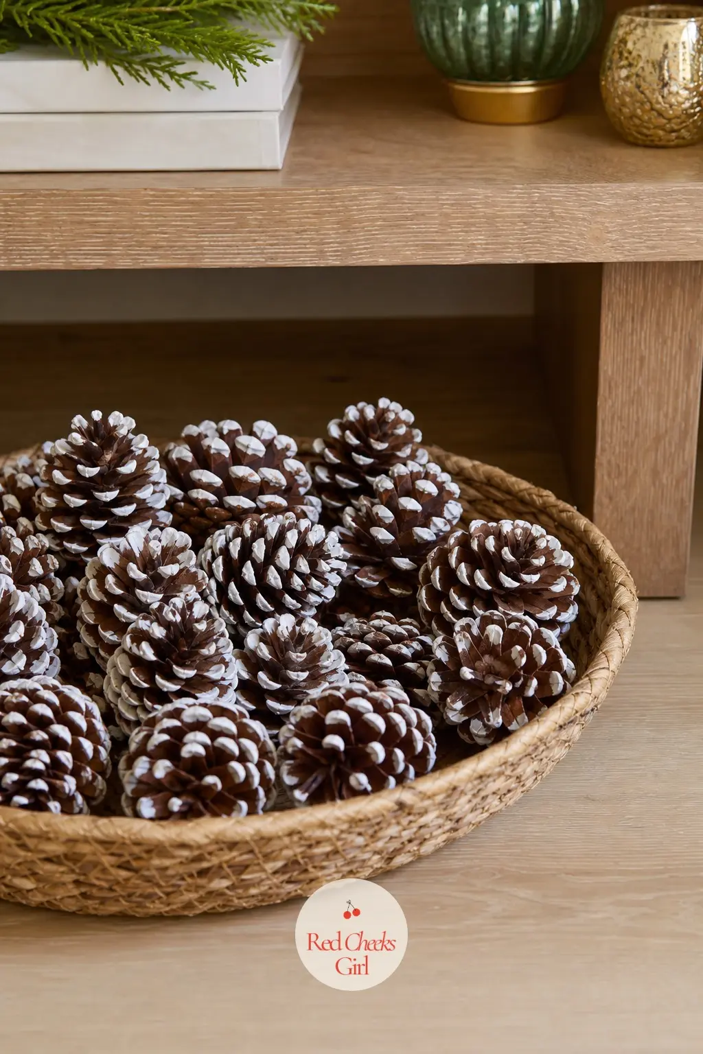 A Low Seagrass Tray of Pinecones Dipped in White Paint — A shallow woven seagrass tray sits on the floor just to one side of the stand, filled with pinecones
