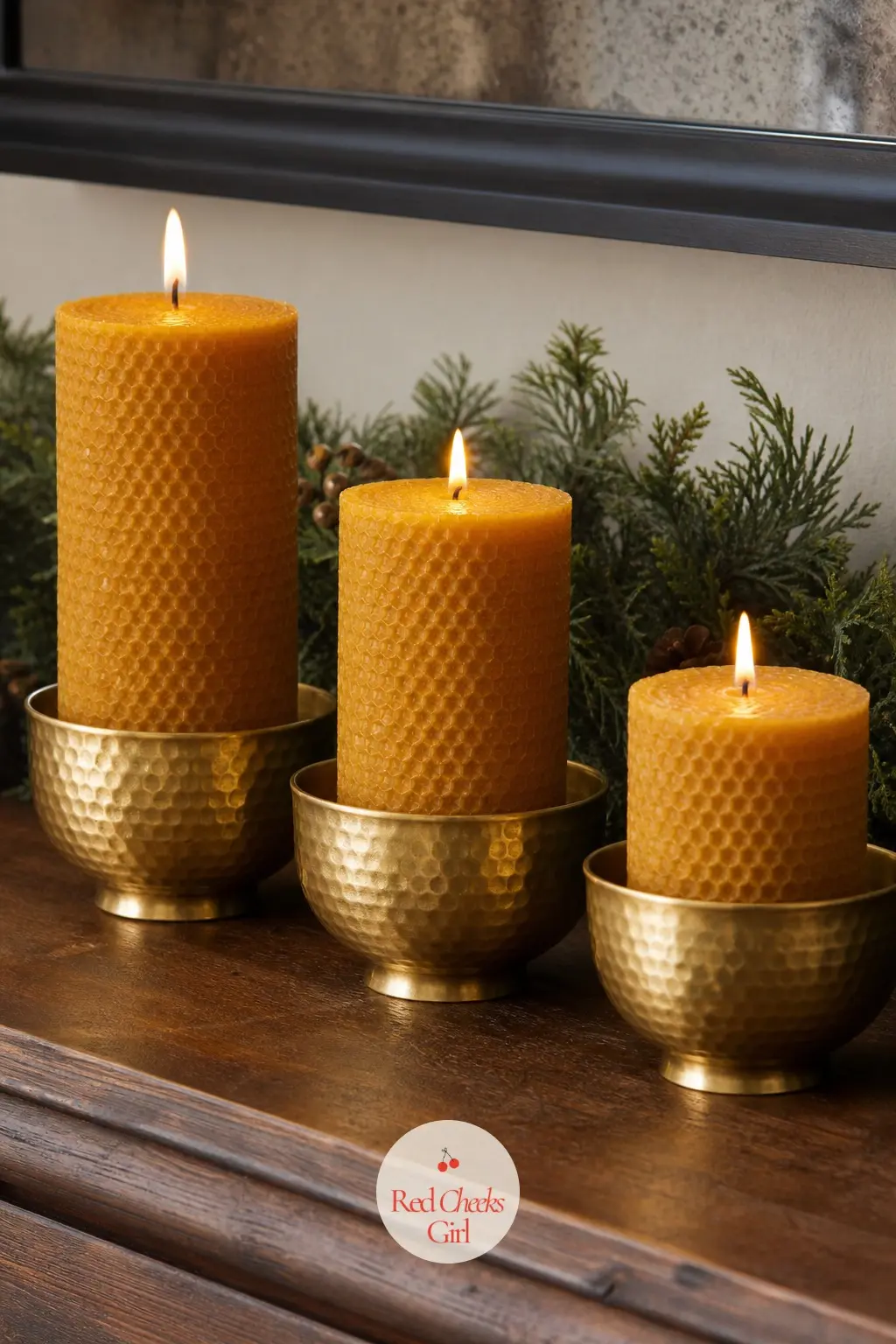 A Row of Amber Beeswax Pillar Candles in Hammered Brass Cups — Three amber beeswax pillar candles of graduated height sit in hammered brass cups along the left