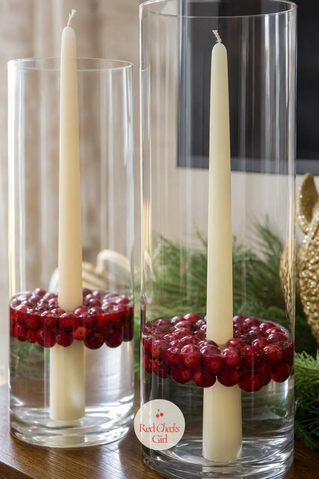 Two Tall Glass Hurricanes With Floating Cranberries and Ivory Taper Candles — A tall glass hurricane sits at each end of the stand, filled a third of the way
