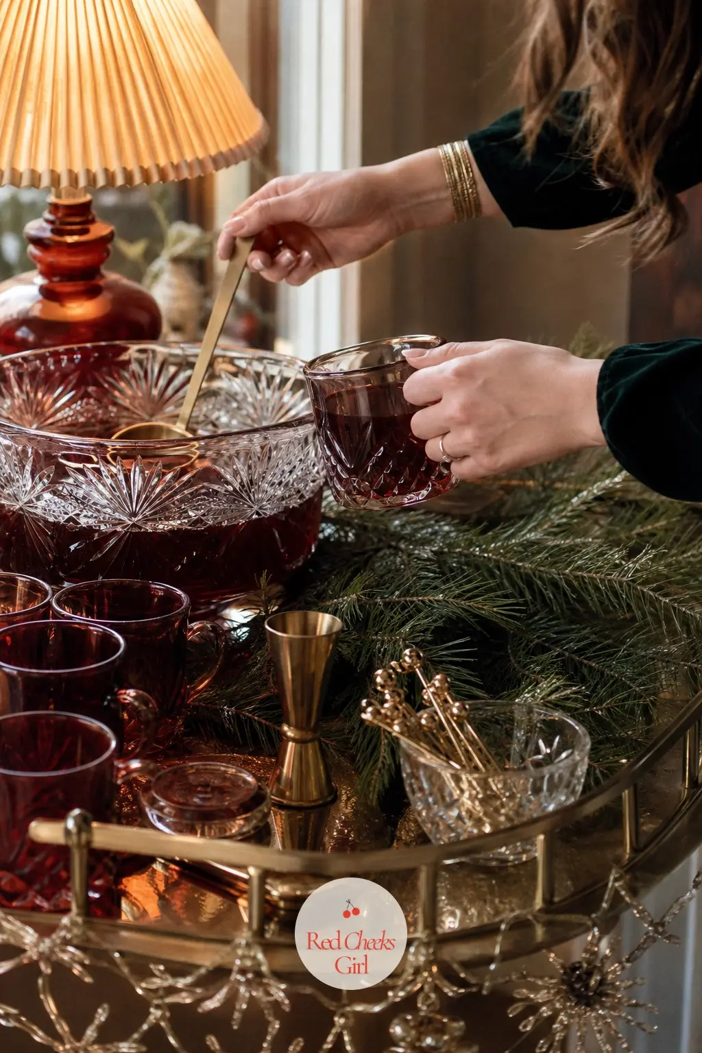 A Hot Drinks Station on the Bar Cart — A bar cart just off the living room holds a cut glass punch bowl for eggnog, cranberry colored glassware, and gold