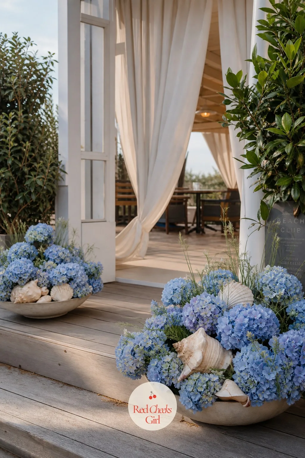 Hydrangea and Shell Entrance Display for a Beach Wedding — Low arrangements of blue hydrangea and pale shells either side of the entrance say coastal without