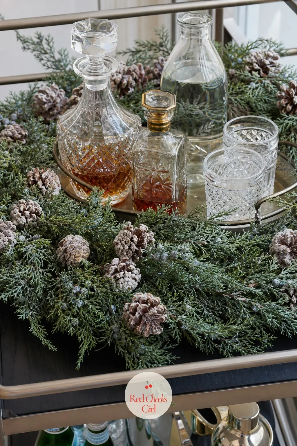 Juniper and Frosted Pinecone Wreath Framing the Drinks Tray — Blue-green juniper sprigs with small frosted pinecones tucked through the branches sit flat