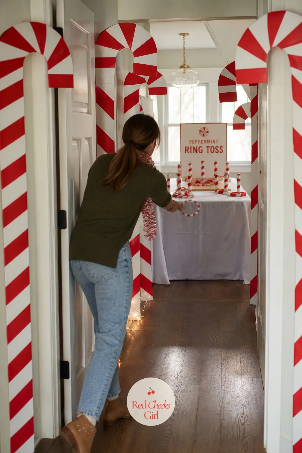 Candy Cane Lane — Red and white striped fabric draped down a hallway, oversized paper candy canes lining the path on either side, and peppermint-scented